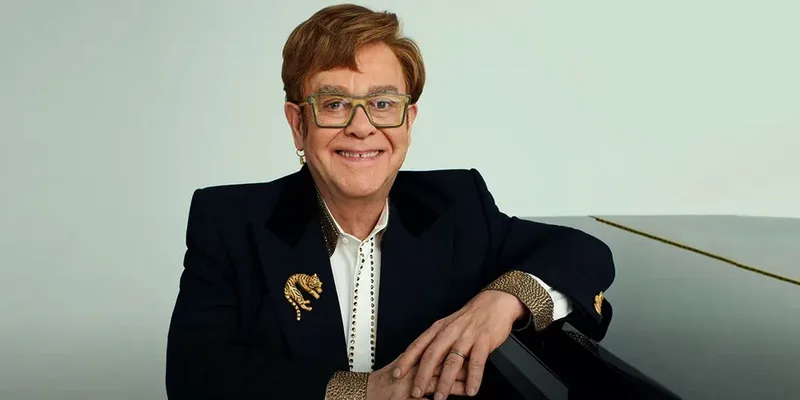 Elton John 坐在钢琴前微笑的照片