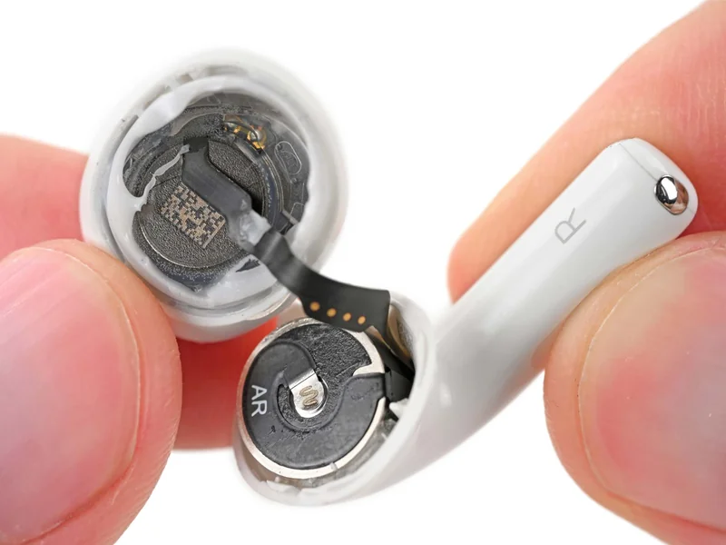 打开的 AirPods 5 耳机内部露出插脚式电池