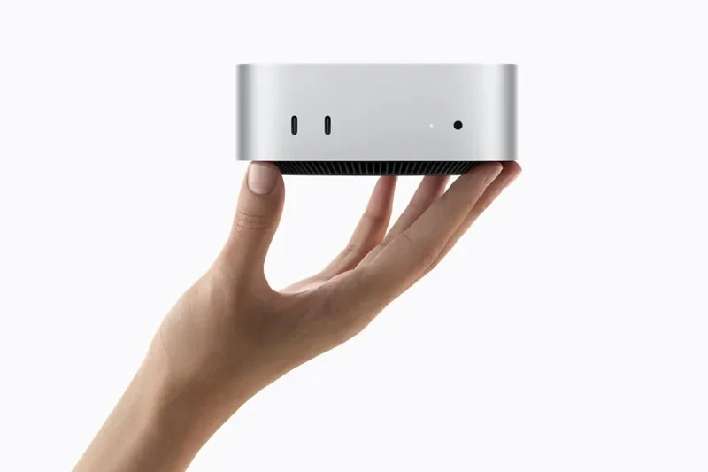 苹果官方 Mac mini 渲染图,银色方形机身被单手托起