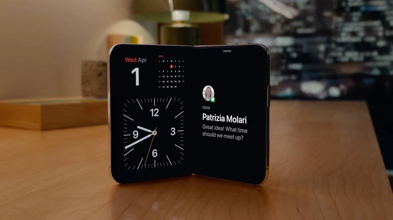 展开的 iPhone Duo 横放在木质桌面上,左半屏显示日历与时钟,右半屏显示信息卡片