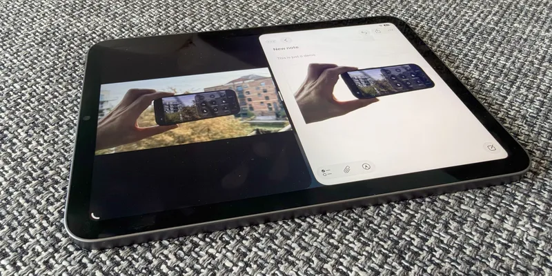iPad mini 平放在织物表面上，屏幕处于分屏状态，左侧显示照片应用，右侧显示备忘录