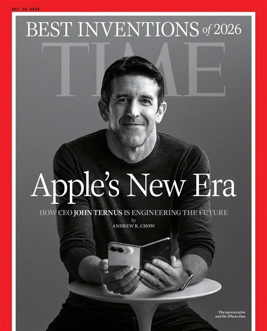 《时代》周刊 2026 年 10 月 26 日刊封面：约翰·特努斯坐在桌前手持两部 iPhone Duo，封面大字为 Apple's New Era，配文「CEO John Ternus 正在为苹果工程出一个未来」