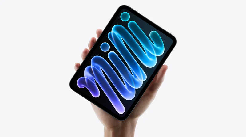 一只手竖持 iPad mini，屏幕显示蓝紫渐变笔刷壁纸，机身背面为深色