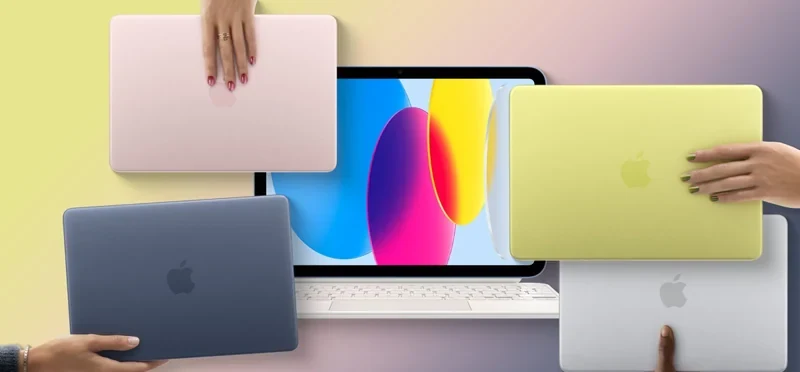 多台不同配色的 MacBook 与一台 iPad 悬浮在浅色渐变背景前，一只手正握着其中一台笔记本的边缘