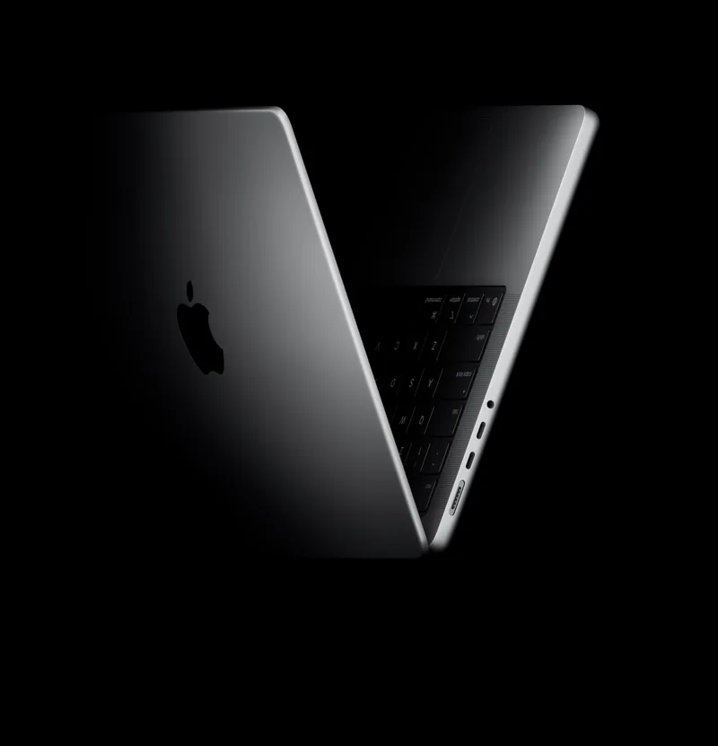 苹果官方 MacBook Pro 产品图，黑色背景下的银色机身与键盘