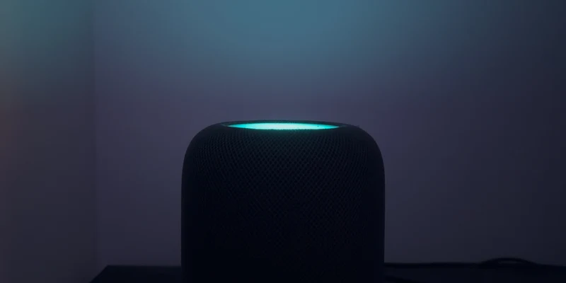 暗光环境下,HomePod 顶部触控面板亮起青色光晕,白墙上映出彩色反光
