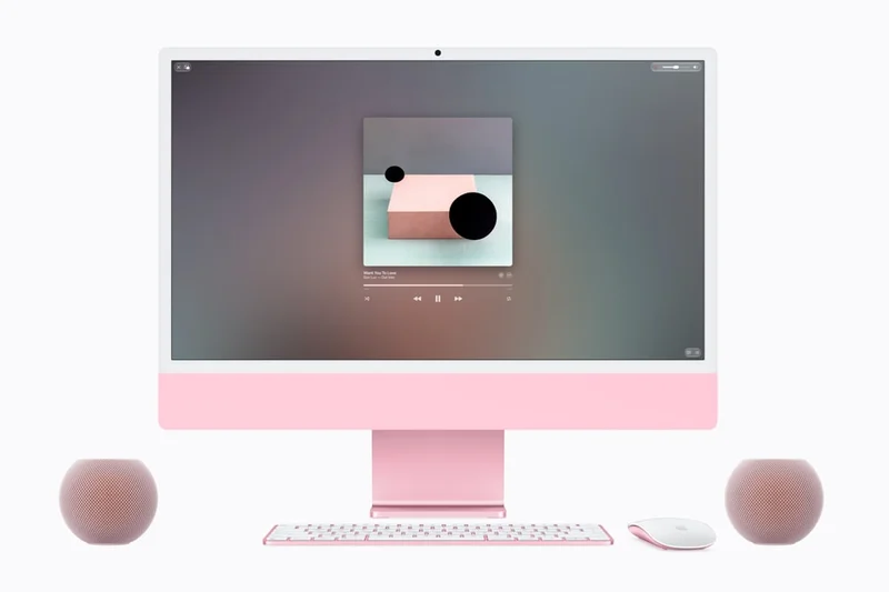 粉色 iMac 居中，左右各放一台粉色 HomePod mini 2，前方是键盘和鼠标，屏幕显示音乐播放界面