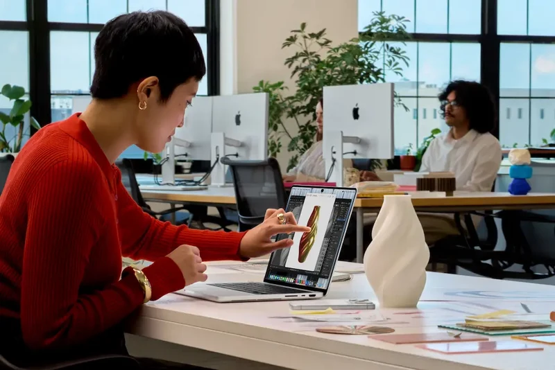办公室场景中一名女性用手指点击 MacBook Pro 屏幕上的图像编辑界面