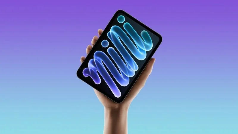 苹果官网风格的 iPad mini 渲染图:一只手举起平板,屏幕上是蓝色与紫色渐变的波纹图案