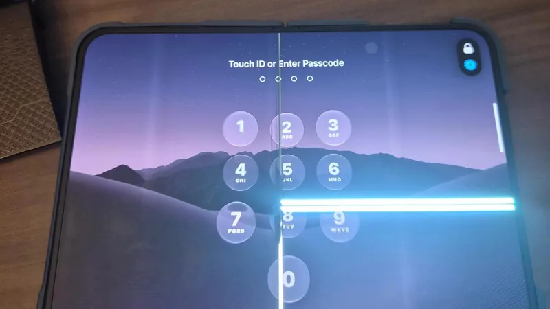 故障实拍：展开的 iPhone Duo 内屏停在锁屏数字键盘界面，折痕处一条竖向亮线自上而下贯穿，中下部另有一条横向亮带穿过数字键区